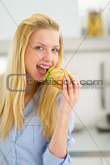 Happy young woman eating sandwich