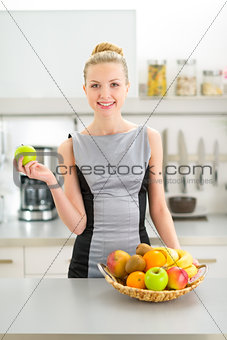 Portrait of happy young woman with fruits in modern kitchen