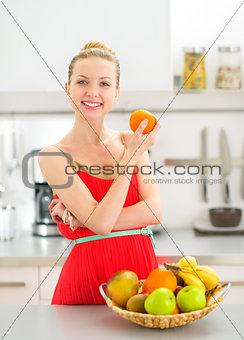 Portrait of happy young woman with fruits in kitchen