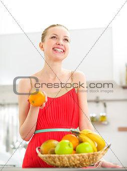 Happy young woman with fruits in kitchen