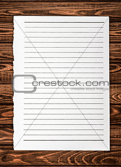 leaf torn from a notebook on a wooden background