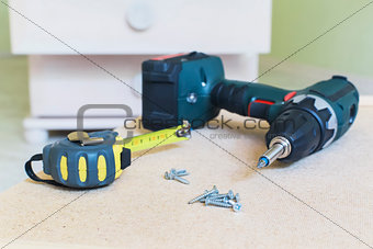 Close-up view of electric screwdriver, screws & tape ruler