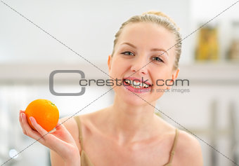 Portrait of happy young woman holding orange