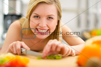 Happy young woman cutting kiwi