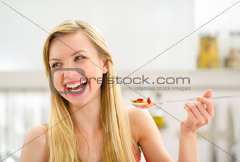 Portrait of happy young woman eating fruits salad