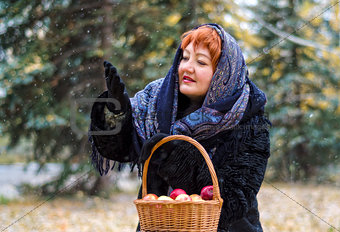 Woman with basket of apples in the forest, comes the first snow
