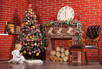 Blonde toddler boy playing near Christmas tree