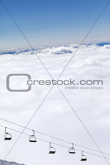 Chair-lift and mountains under clouds in sun day