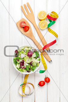 Fresh healthy salad, utensils and tape measure