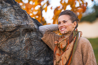Portrait of happy young woman in autumn park in evening