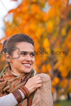 Portrait of happy young woman in autumn outdoors in evening