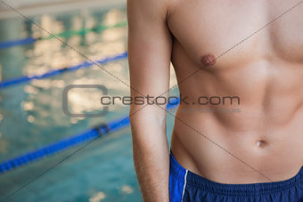 Mid section of a shirtless fit swimmer by pool