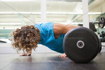 Side view of young man doing push ups in gym
