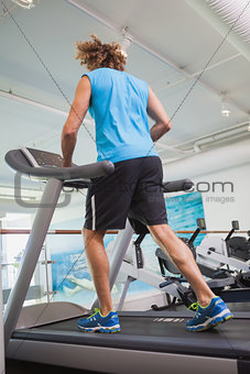 Rear view of man running on treadmill in gym