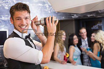 Handsome barman smiling at camera making a cocktail