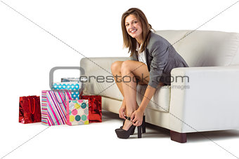 Well dressed woman sitting on couch taking off her shoes