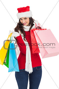 Smiling brunette in winter wear holding shopping bags