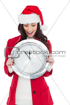Excited brunette holding a clock
