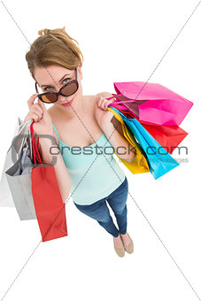 Blonde looking over her sunglasses while holding bags