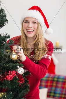 Smiling woman hanging christmas decorations on tree