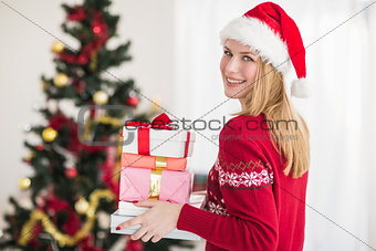 Blonde holding pile of gifts in front of the christmas tree