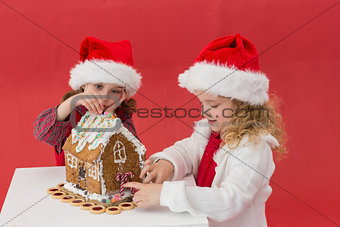 Festive little girls making a gingerbread house