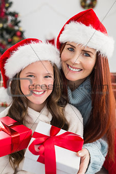 Festive mother and daughter exchanging gifts