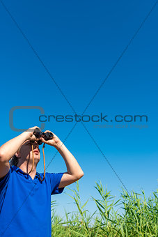 man looking through binoculars into the sky