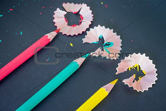 Different color pencils shavings on dark background