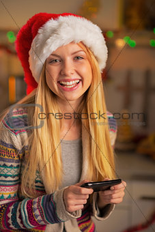 Happy teenager girl in santa hat writing sms