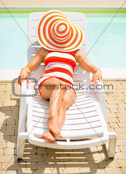 Young woman laying on sunbed with hat on head