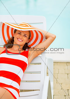 Portrait of smiling young woman in hat sitting laying on chaise-