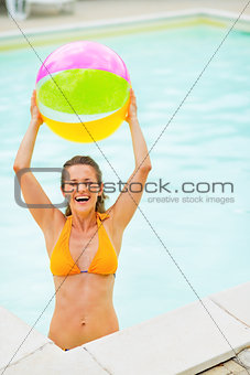 Portrait of smiling young woman with beach ball in pool