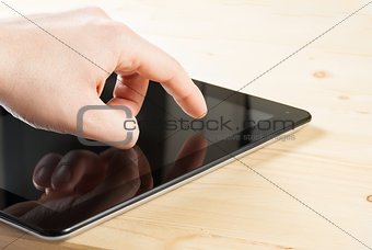 male hand is touching digital tablet pc on wood table