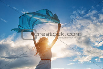 Beautiful young woman holding blue scarf on the wind 