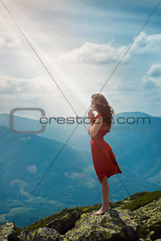 Beautiful woman praying in mountain landscape