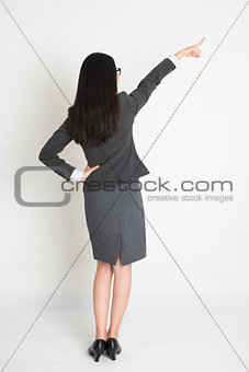 Full length backside Asian business woman pointing