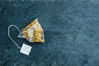 Closeup on camomile tea bag on stone substrate