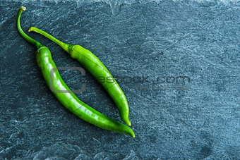 Closeup on green chili peppers on stone substrate