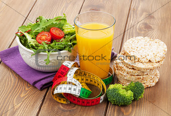 Healthy food and tape measure over wooden table