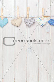 Valentines day toy hearts hanging on rope over white wooden back