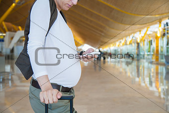 pregnant touching phone in airport
