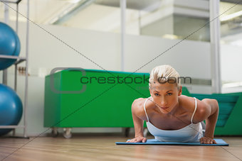 Beautiful woman doing push ups in in fitness studio