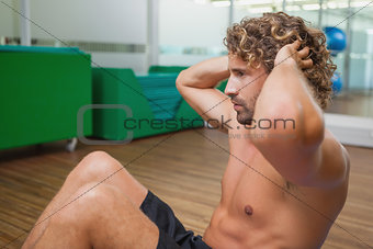 Side view of shirtless man doing push ups in gym