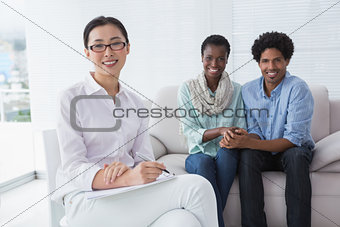Reconciled couple smiling at camera with therapist