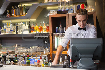Handsome barman standing at the cash register
