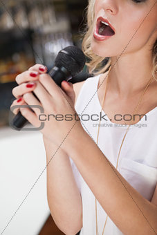 Close up of beautiful blonde singing into a microphone