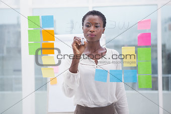 Businessman with short hair writing on clear board