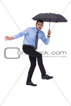 Anxious businessman under umbrella balancing