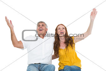 Casual couple smiling with arms raised
